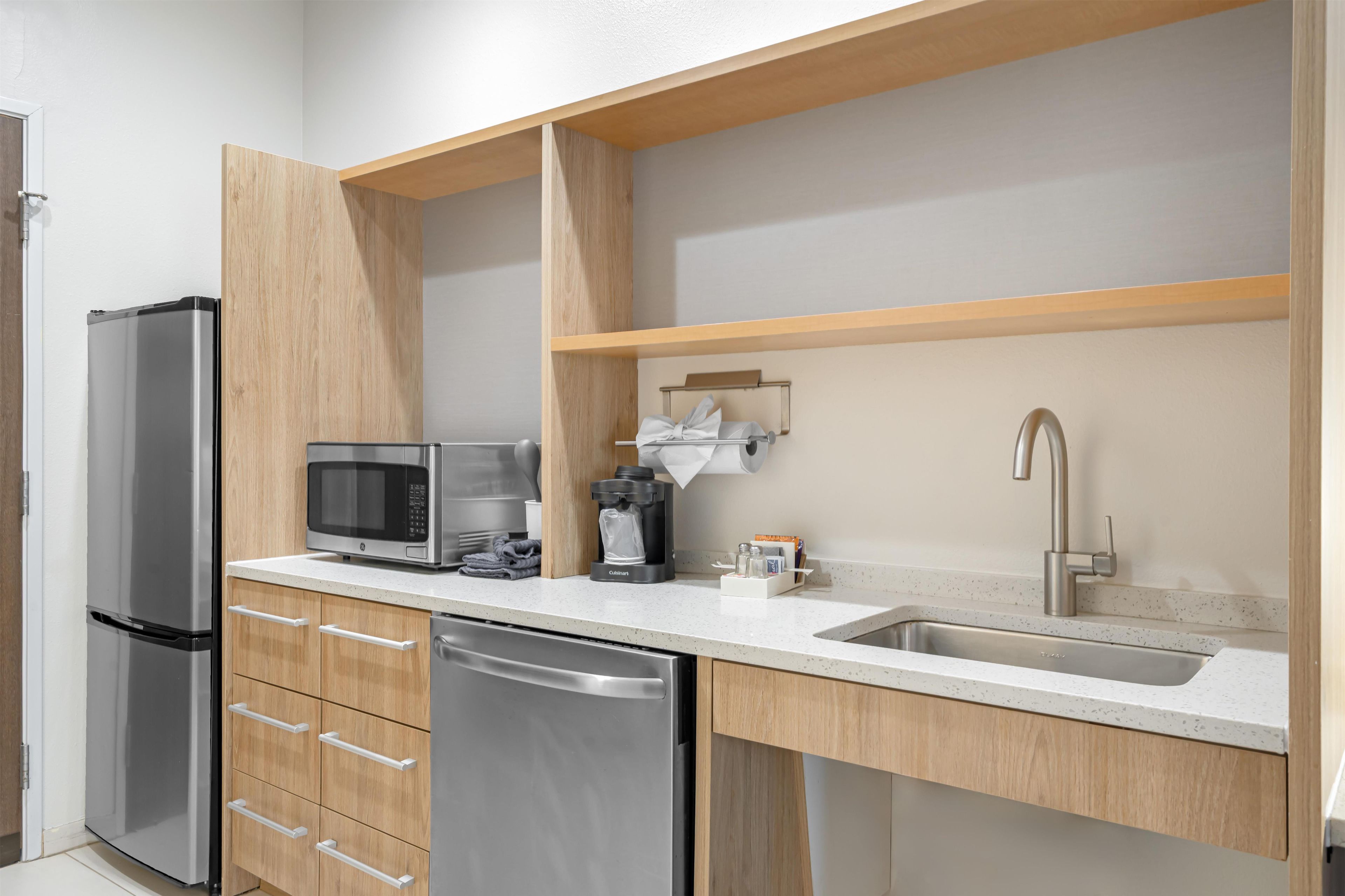A modern kitchen with a stainless steel refrigerator, microwave, coffee maker, and dishwasher.