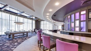A modern bar area with a long counter, bar stools, and a seating area with a table and chairs. - Hampton Inn & Suites Fort Worth Downtown (Fort Worth)