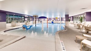 An indoor swimming pool with a blue dolphin decoration, lounge chairs, and tables. - Hampton Inn & Suites Fort Worth Downtown (Fort Worth)