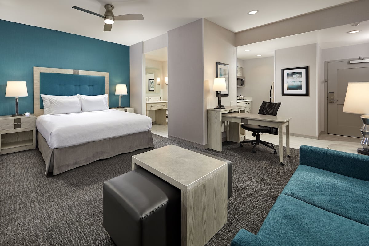 A hotel room with a bed, desk, and seating area.