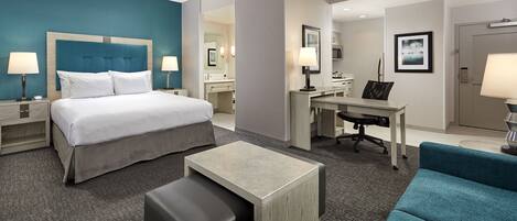 A hotel room with a bed, desk, and seating area.