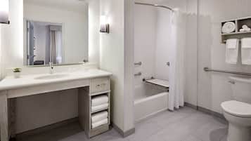 Un baño moderno con un espejo grande, un lavamanos, una bañera y un inodoro.