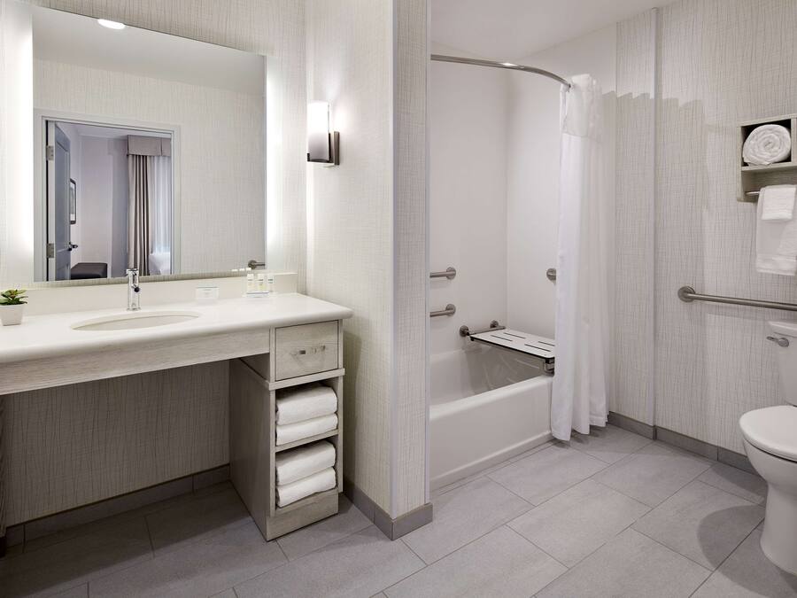 Un baño moderno con un espejo grande, un lavamanos, una bañera y un inodoro.