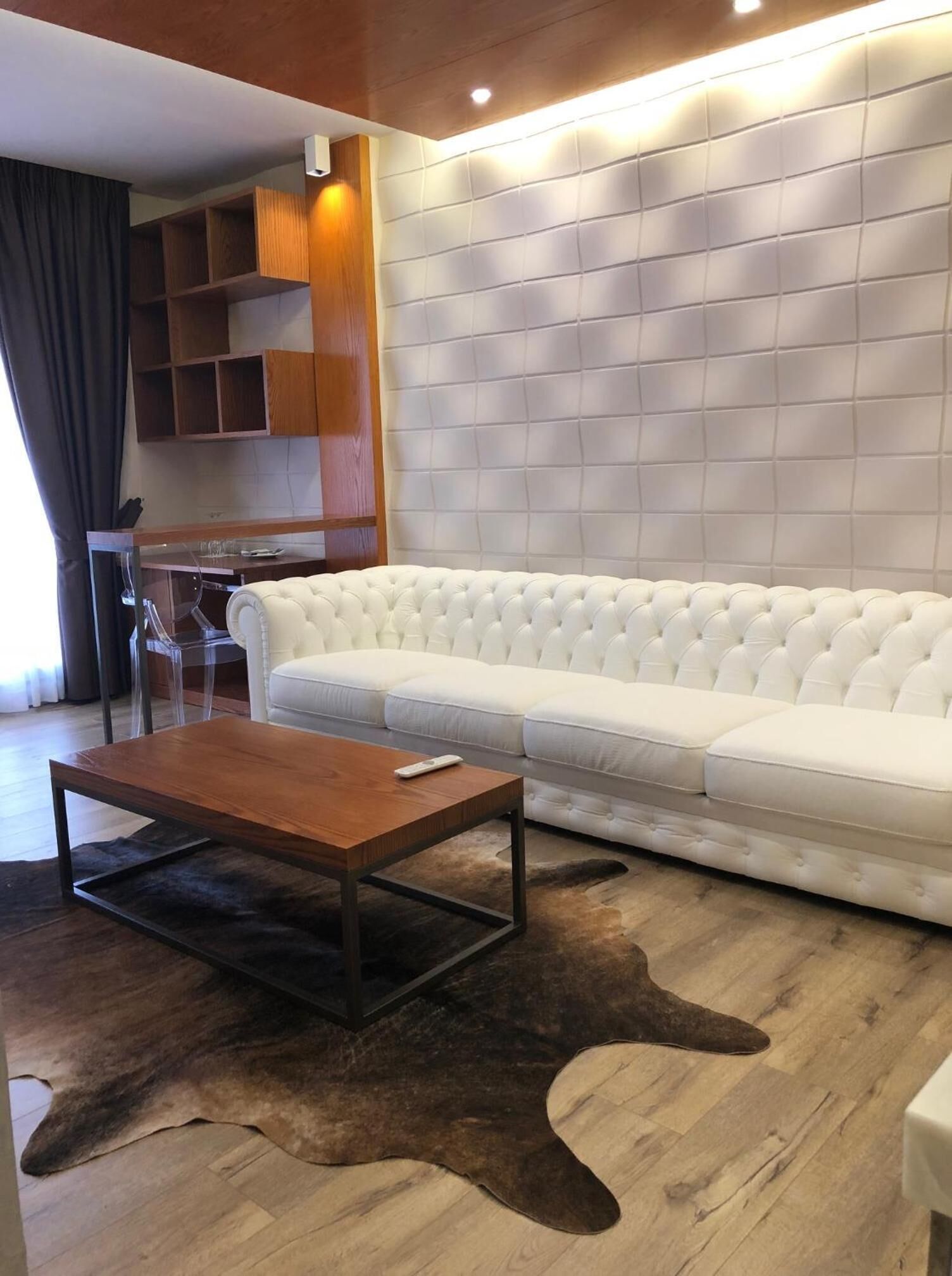 Una sala de estar moderna con un sofá blanco, una mesa de centro de madera y una alfombra de cuero.