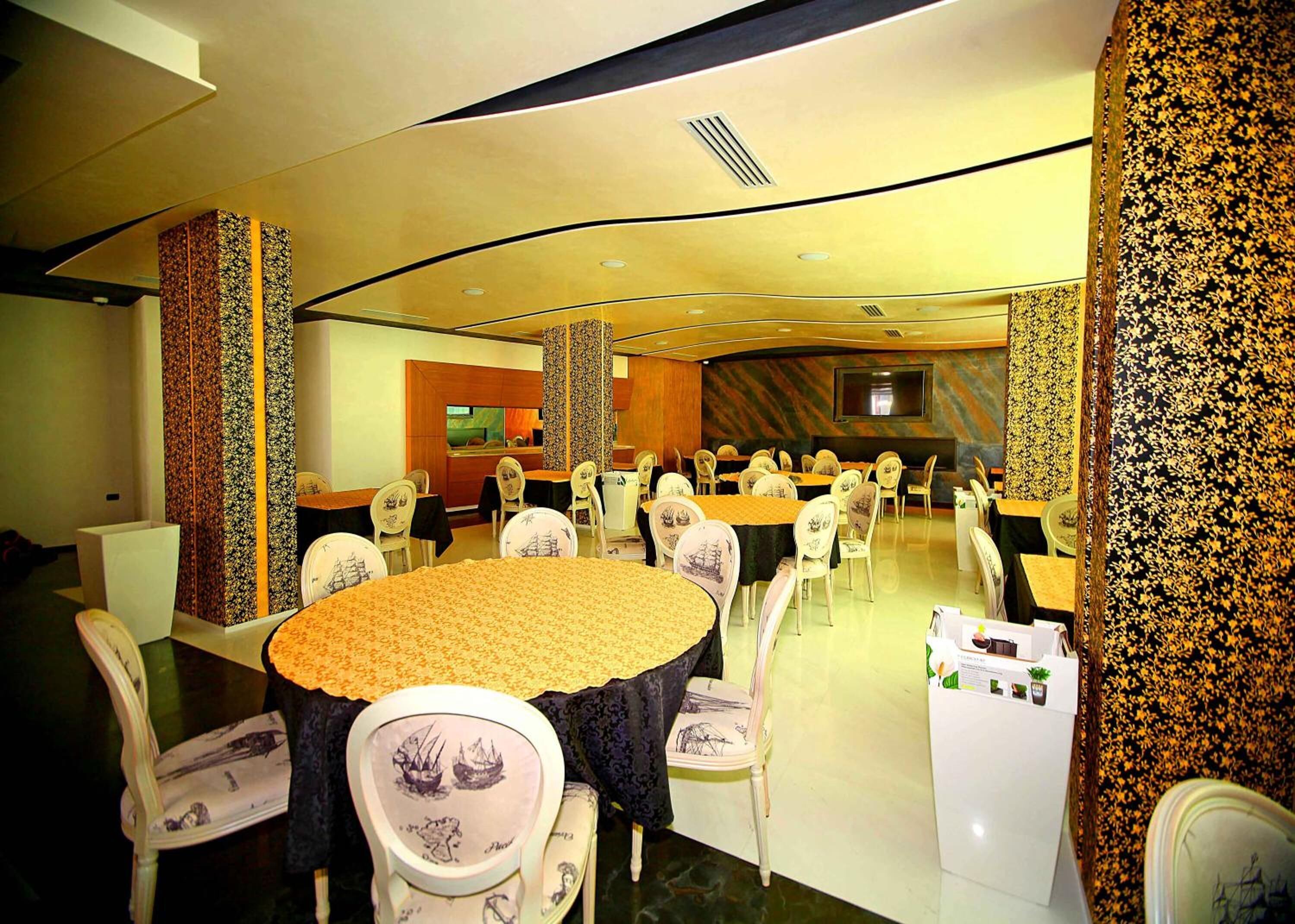 A conference room with round tables and chairs, a large screen, and patterned wallpaper.
