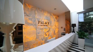 Un espace d’accueil avec un mur en marbre, un comptoir de réception et un escalier.