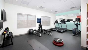 A fitness center with treadmills, elliptical machines, a bench press, and a variety of weights.
