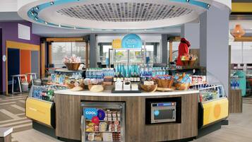 A modern, circular counter with a variety of food and drink items, a refrigerated display, and a digital kiosk.