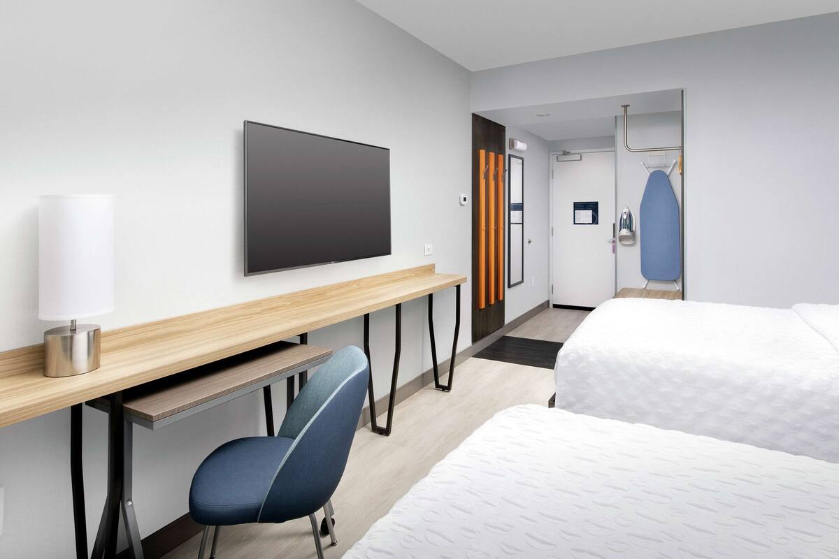 Ein Hotelzimmer mit Bett, Schreibtisch mit Stuhl, Fernseher und Duschbereich.