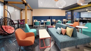 A modern lounge area with seating arrangements, including sofas, chairs, and a hanging chair. - Tru by Hilton Louisville East (Louisville)