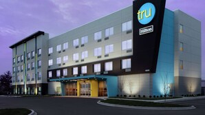 A modern hotel with a prominent 'tru Hilton' sign, multiple floors, and a well-lit entrance. - Tru by Hilton Louisville East (Louisville)