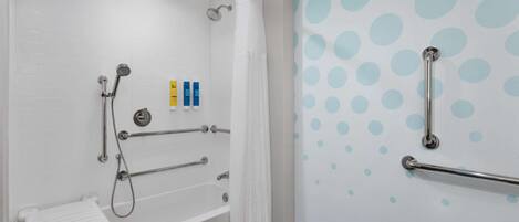 Un baño moderno con bañera, ducha y barras de apoyo.