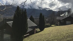 A rural landscape with a house featuring a sloped roof and a chimney emitting smoke. - Cabañas en Pucon con vista cordillera (Pucón)