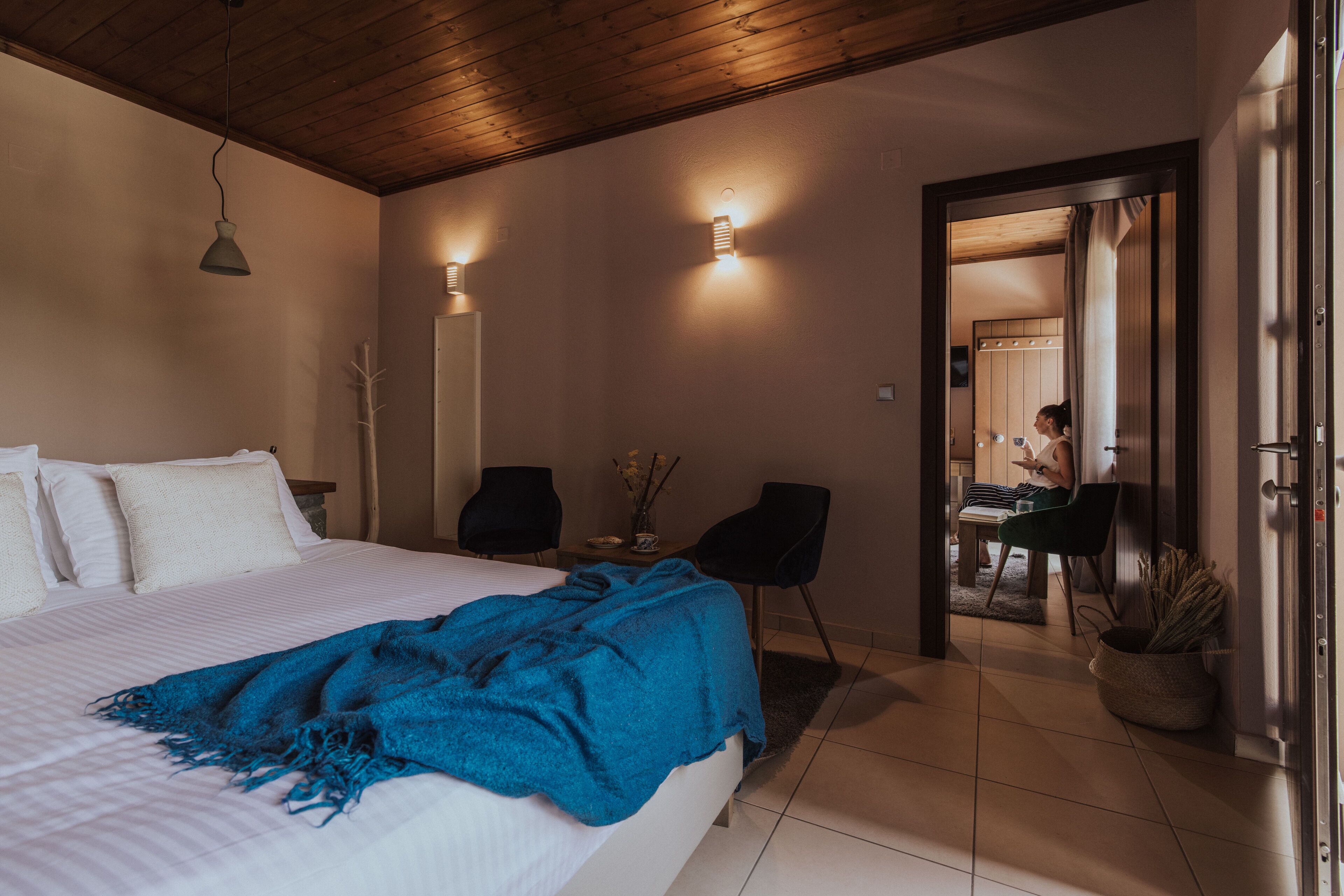 Una camera da letto con un letto, una coperta blu, una scrivania con una sedia e una porta che dà su un'altra stanza.