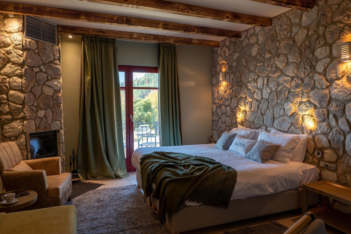 A bedroom with a stone wall, a bed, a chair, and a fireplace.
