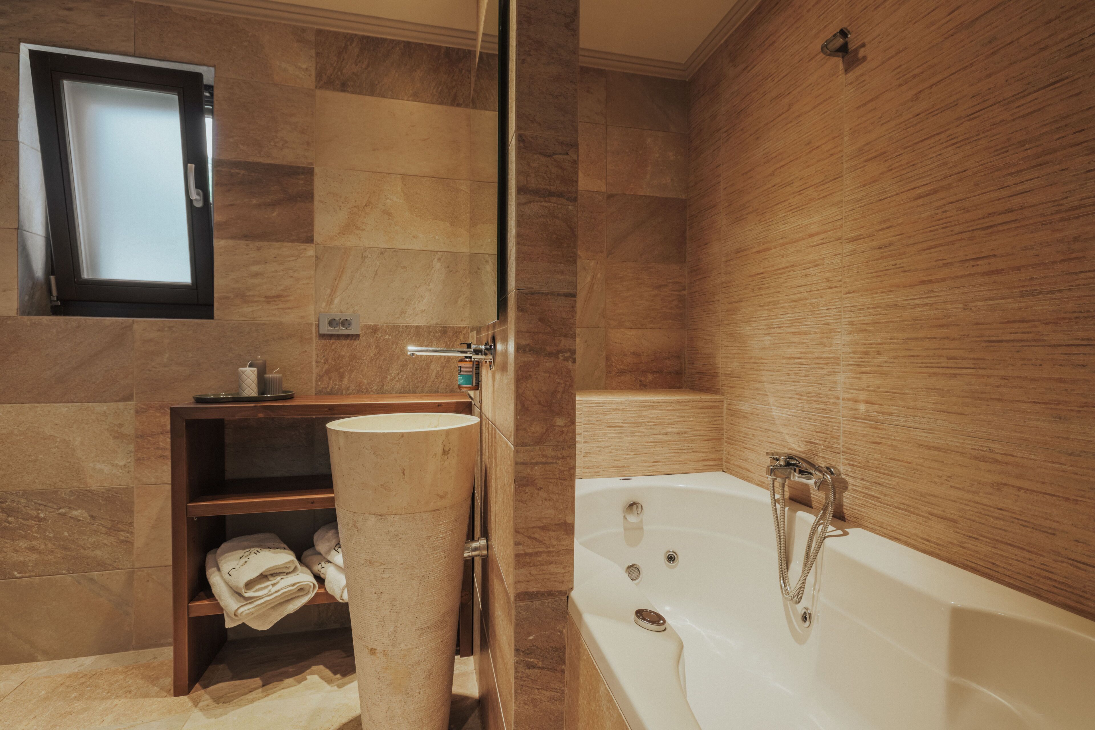 Une salle de bain moderne avec une baignoire, un lavabo et une étagère où sont rangées les serviettes.