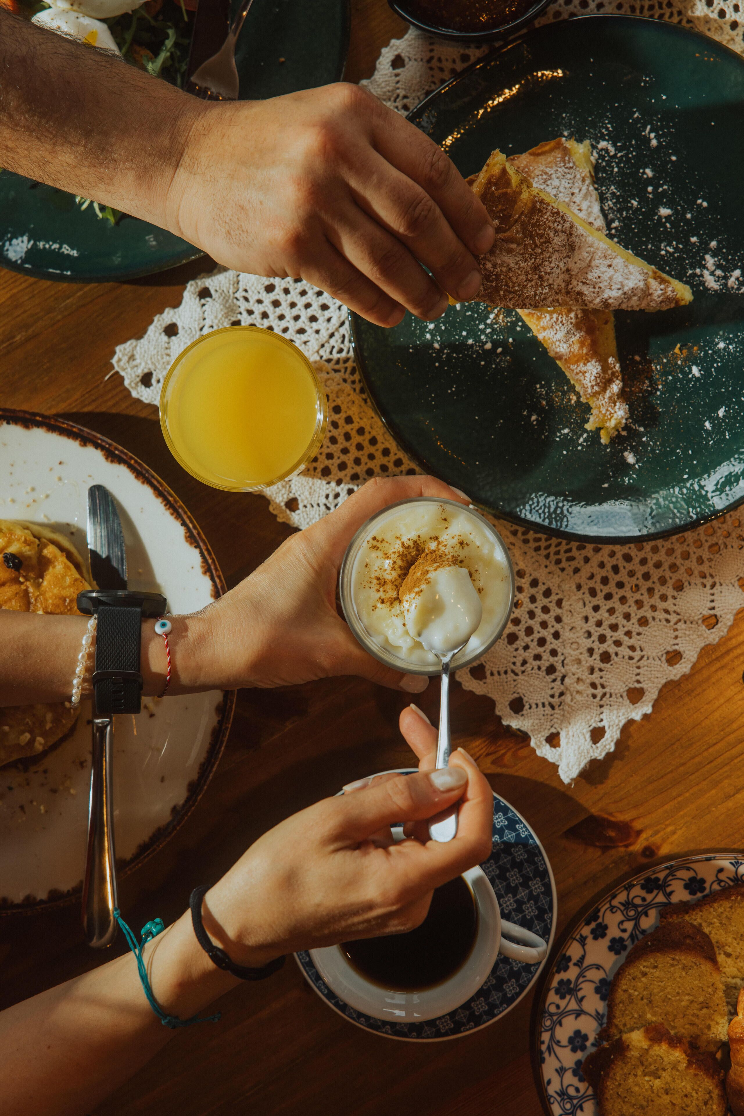 Una mesa de comedor con platos de comida, un vaso de jugo de naranja y una taza de café.