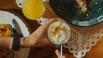 Una mesa de comedor con platos de comida, un vaso de jugo de naranja y una taza de café.