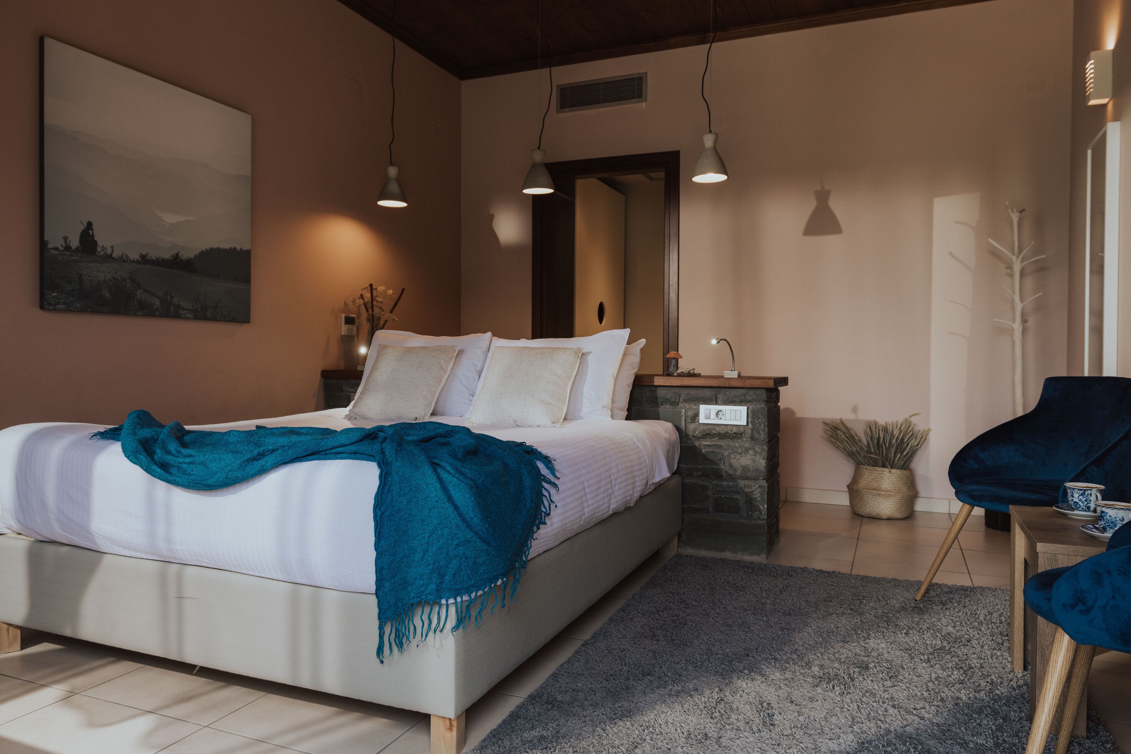 Un dormitorio moderno con una cama grande, mesitas de noche, un espejo y una silla azul.