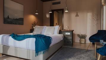 Un dormitorio moderno con una cama grande, mesitas de noche, un espejo y una silla azul.