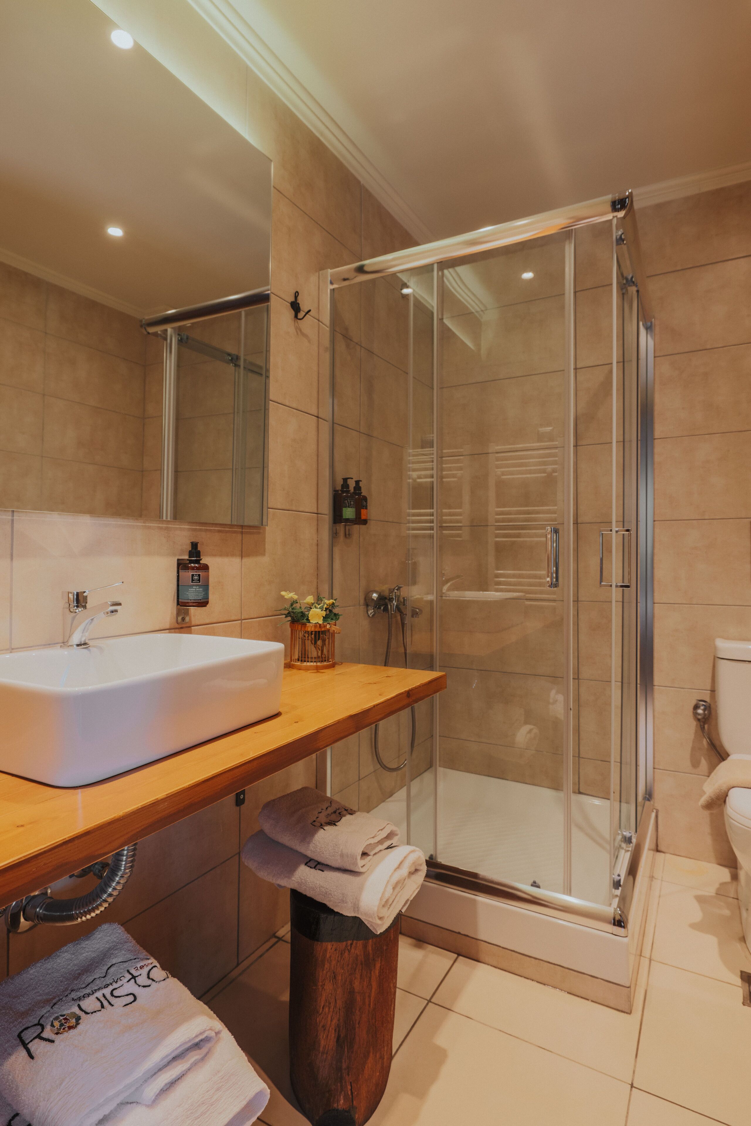 A modern bathroom with a glass-enclosed shower, a large sink, and a mirror above it.