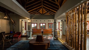 A spacious living area with a high ceiling, a central seating area, and a view of the outdoors through large windows. - Rouista Tzoumerka Resort (Central Tzoumerka)