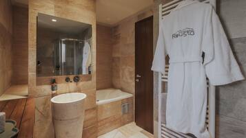 Un baño moderno con bañera, un espejo grande, un lavabo y un perchero con una bata.