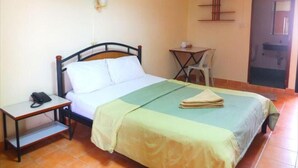 A single bed with a wooden frame, a bedside table with a phone, a small table with a chair, and a door with a mirror. - Utid Court (Pattaya)