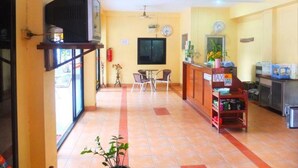 A hotel lobby with a reception desk, a television on a stand, a clock, and a fire extinguisher. - Utid Court (Pattaya)