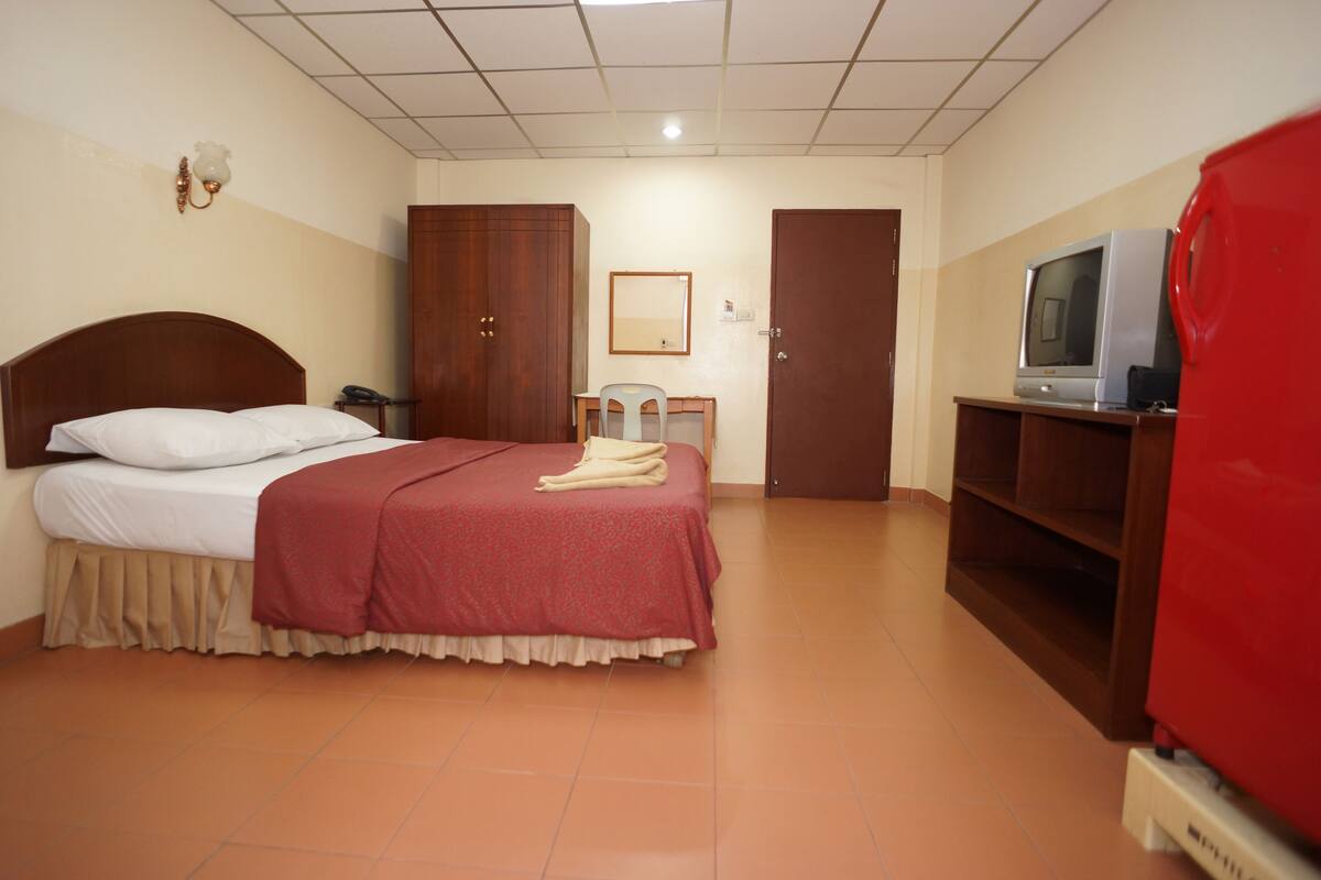 Une chambre d’hôtel équipée d’un lit, d’un bureau, d’une télévision et d’une armoire.