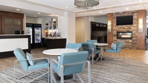 Een hotellobby met zithoeken, een bar, een open haard en een aan de muur bevestigde televisie.