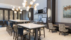 A modern dining area with a large table, multiple chairs, and a unique chandelier. - Hampton  Inn & Suites Indianapolis-Keystone (Indianapolis)
