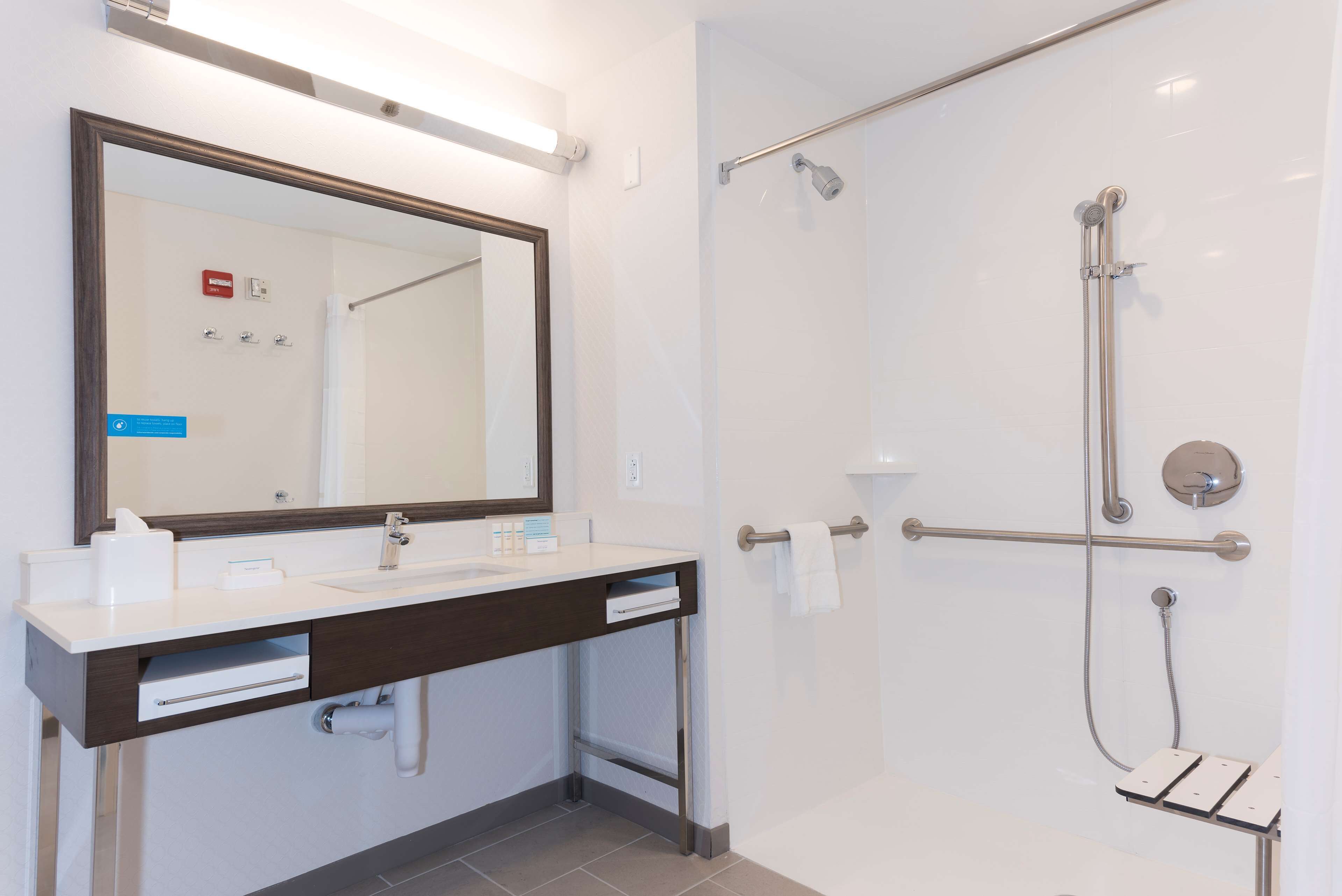 A modern bathroom with a large mirror, a sink, and a glass-enclosed shower area.