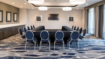 A conference room with a long table, chairs, and a large window with curtains.