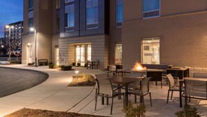 An outdoor patio area with seating and a fire feature, surrounded by a brick building with multiple windows. - Hampton  Inn & Suites Indianapolis-Keystone (Indianapolis)