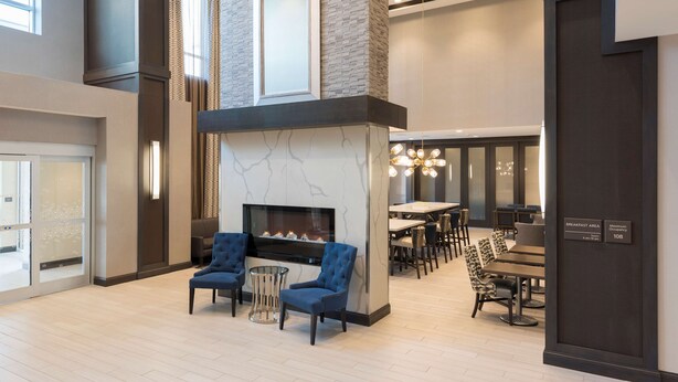 A modern hotel lobby with a fireplace, seating area, and breakfast space. - Hampton  Inn & Suites Indianapolis-Keystone (Indianapolis)