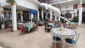 A spacious indoor area with multiple dining tables and chairs, a staircase, and various potted plants. - Hotel Las Catalinas Antón (Anton)