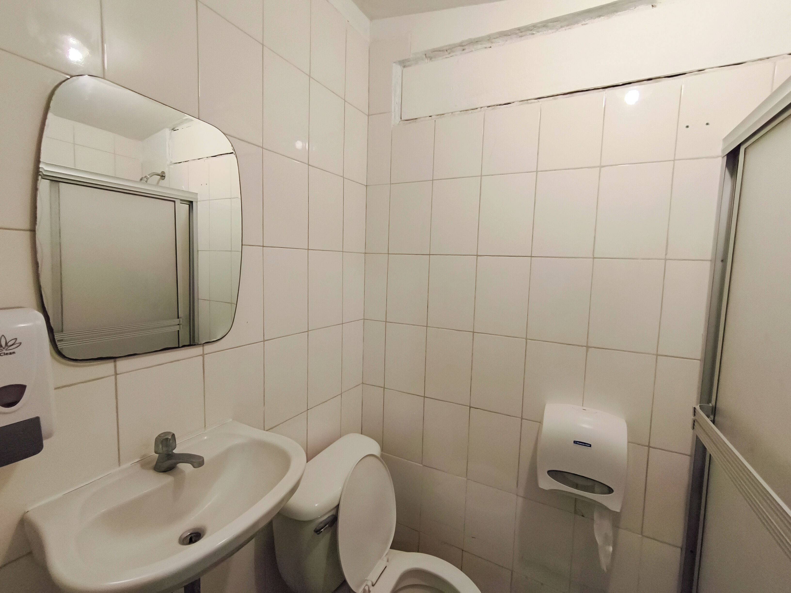 A bathroom with a sink, toilet, mirror, and hand dryer.