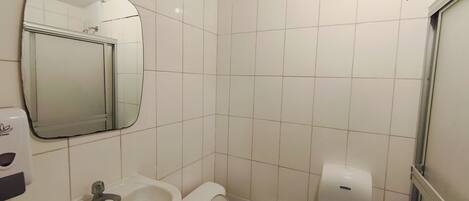 A bathroom with a sink, toilet, mirror, and hand dryer.