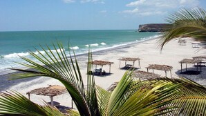 A beach with clear skies, calm sea, and thatched umbrellas. - Hotel Las Catalinas Antón (Anton)