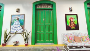 A room with a green door, a bed with floral bedding, and two potted plants. - Hotel Las Catalinas Antón (Anton)
