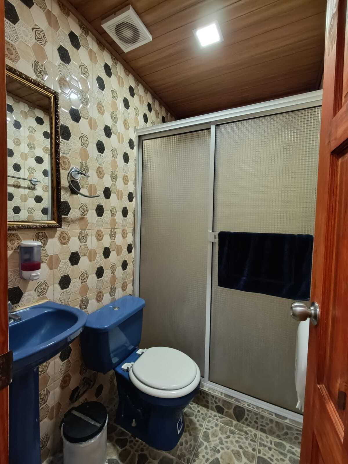 Un baño con ducha, dos lavamanos, inodoro y espejo.