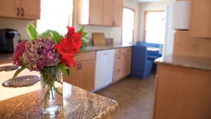 Eine Küche mit Holzschränken, einer Granit-Arbeitsplatte und einer Vase mit Blumen.