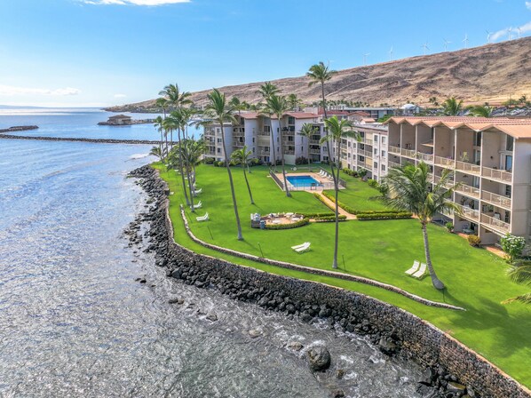 Un resort con piscina, palmeras y vista al océano.