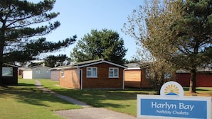 Un letrero de Harlyn Bay Holiday Chalets, con un camino despejado que lleva a las cabañas.