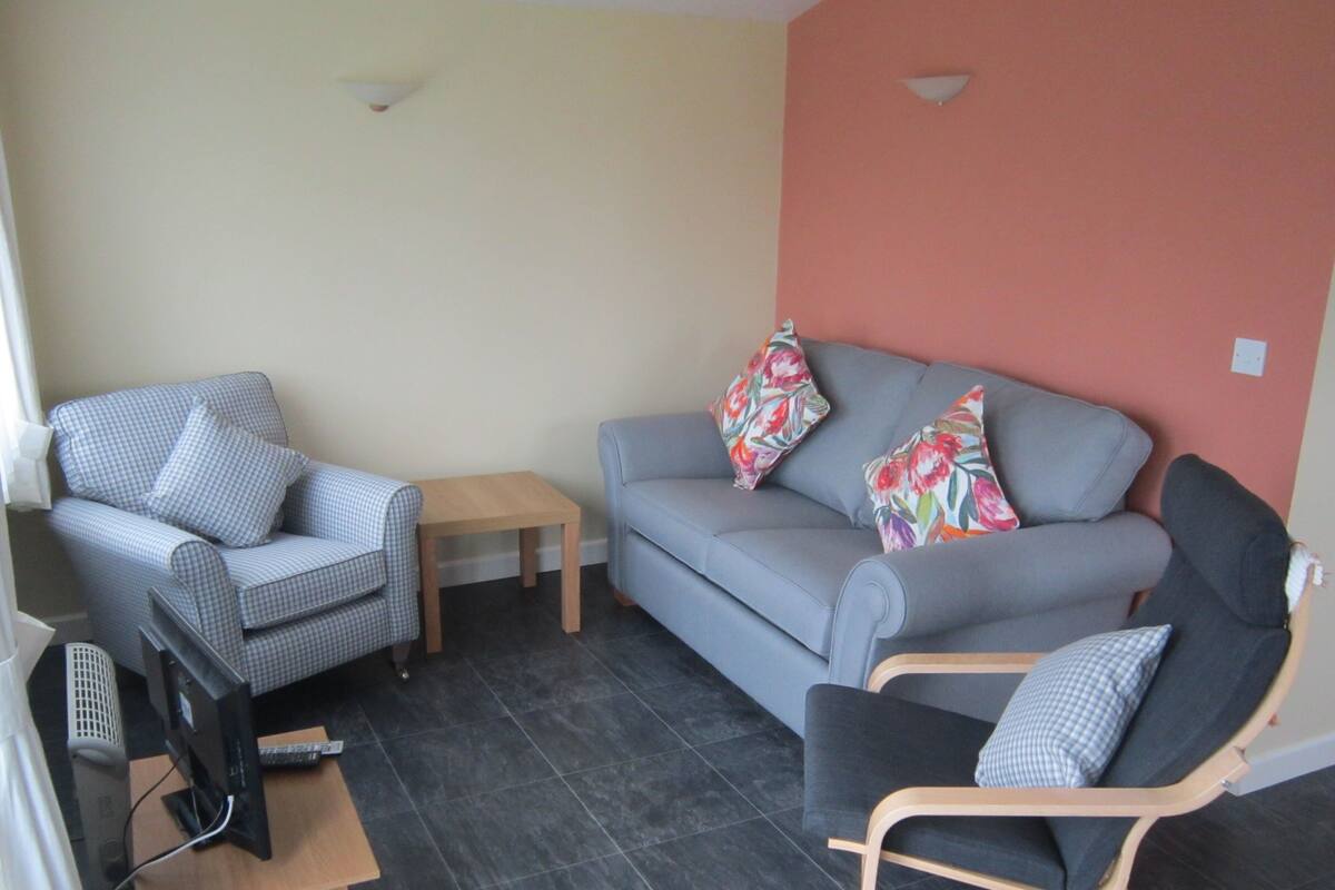 Una sala de estar con un sofá gris, un sillón azul y una mesita.
