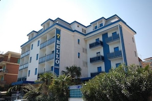 A multi-story hotel with balconies, a prominent 'BELLO' sign, and a clear sky.