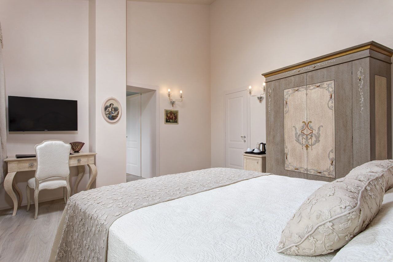 A bedroom with a bed, a desk, a television, and a wardrobe.
