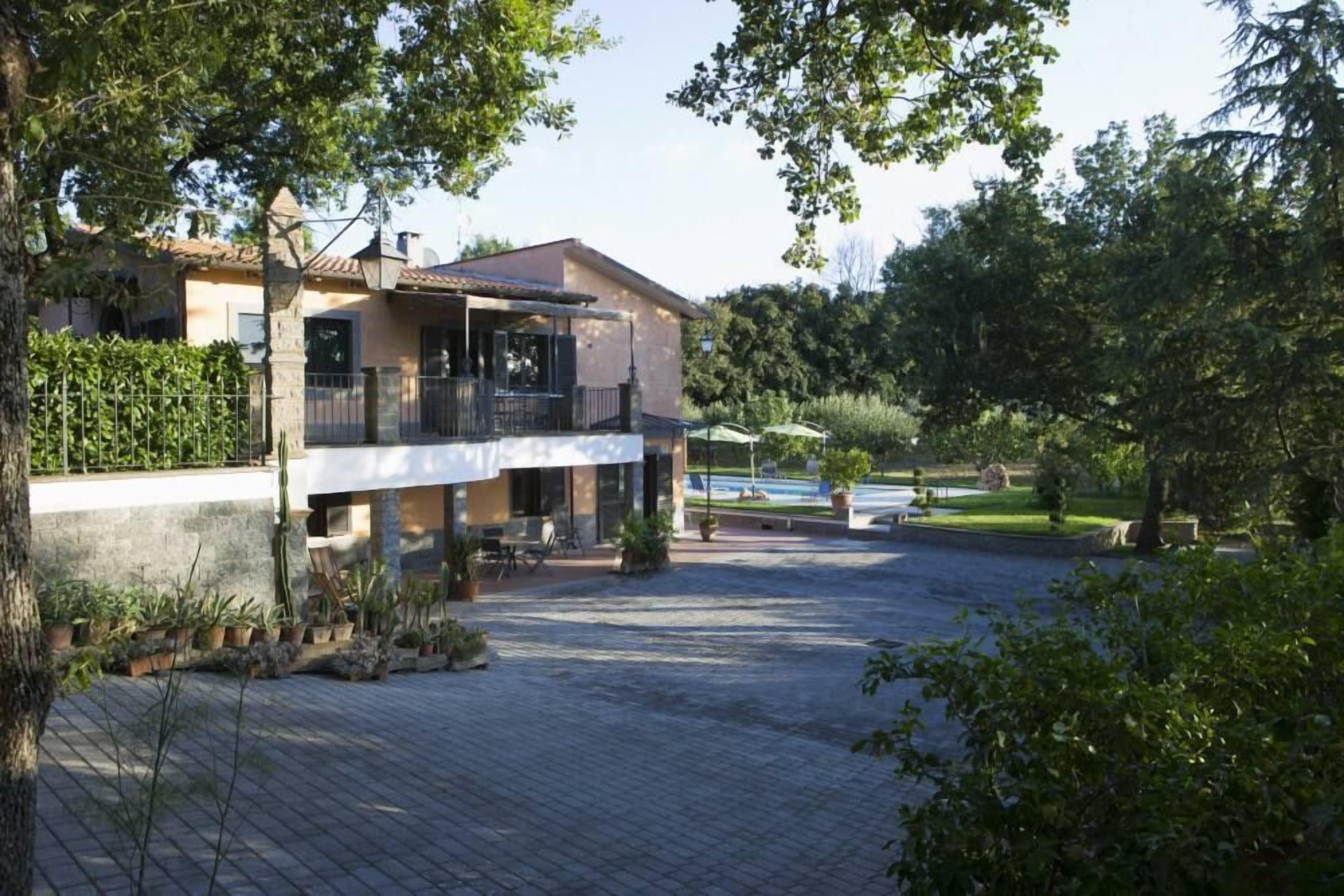 Una casa de dos plantas con balcón, piscina y entrada pavimentada.