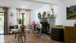 Una sala de estar acogedora con chimenea, una mesa de comedor con sillas y vistas al exterior.
